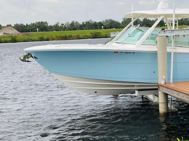 Slide: The Image of 2021 Cobia 330 Dual Console boat docked on a lift in a serene waterway. - 5