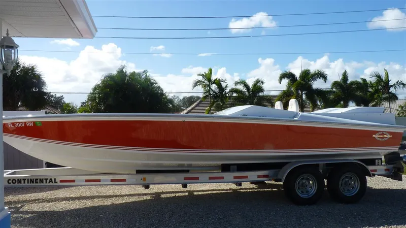 Slide: The Image of 1971 Magnum Sport boat on a Continental trailer, red and white, parked outdoors. - 2