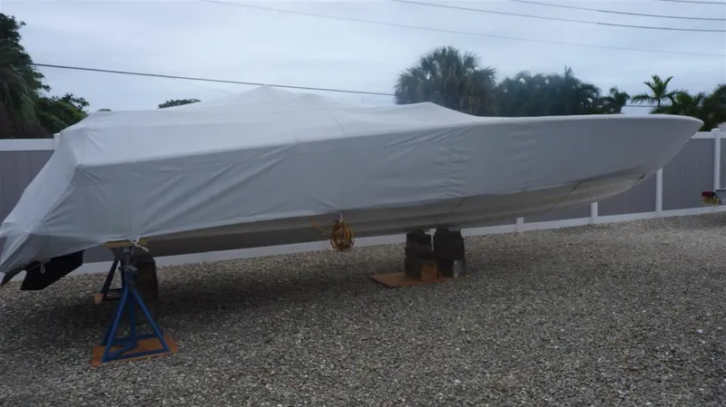 Slide: The Image of 1971 Magnum Sport boat covered and elevated on stands in a gravel yard. - 22