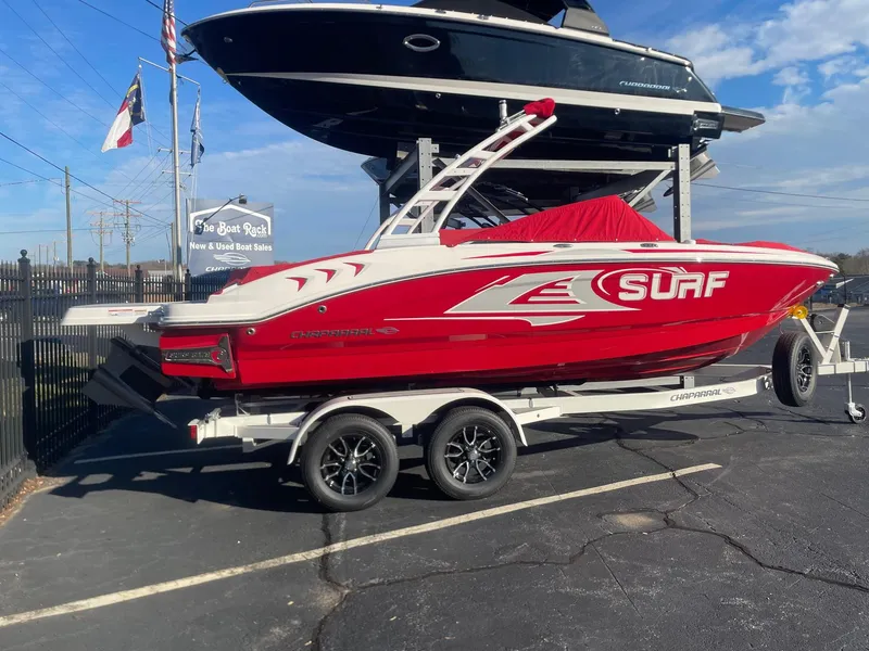 Slide: The Image of 2023 Chaparral 21 Surf boat in red, displayed on a trailer at a dealership. - 1