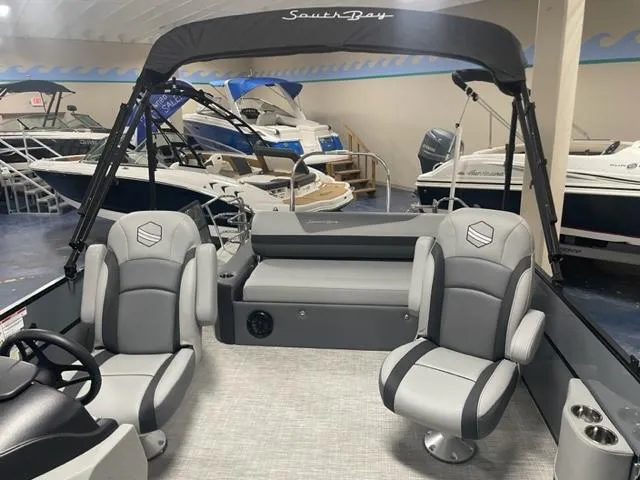 Slide: The Image of 2023 South Bay 224 UL 3.0 pontoon boat interior with gray seating in showroom. - 10