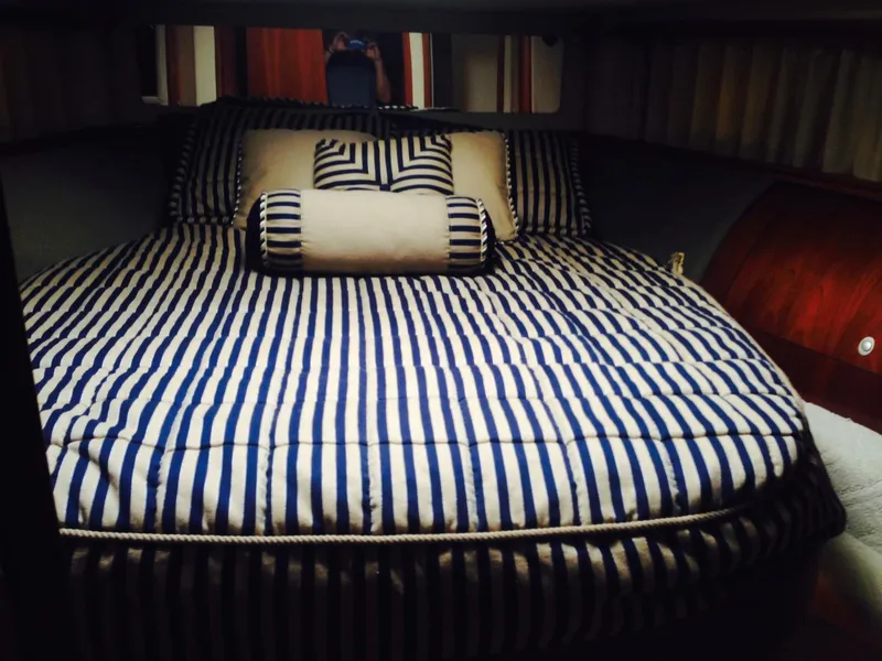 Slide: The Image of 2005 Sea Ray 550 Sedan Bridge bedroom with striped bedding and pillows - 16