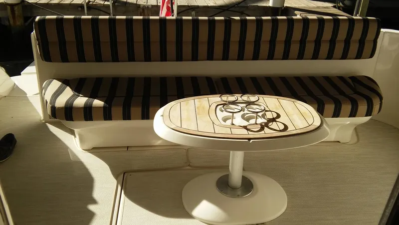 Slide: The Image of 2005 Sea Ray 550 Sedan Bridge boat interior with striped seating and wooden table. - 8