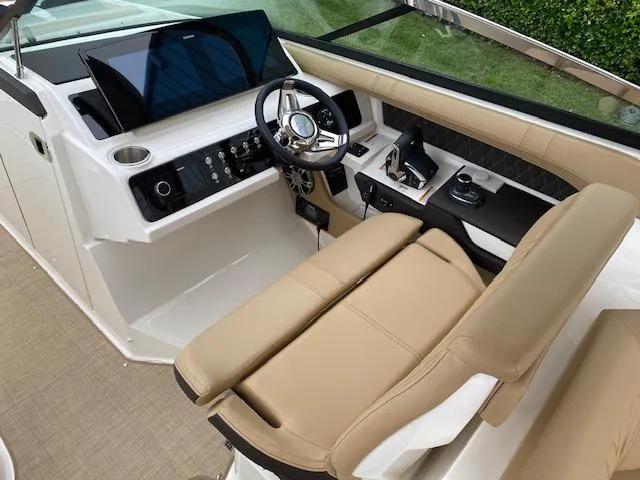 Slide: The Image of 2023 Sea Ray SLX 310 OB boat helm with beige seating and modern controls. - 24
