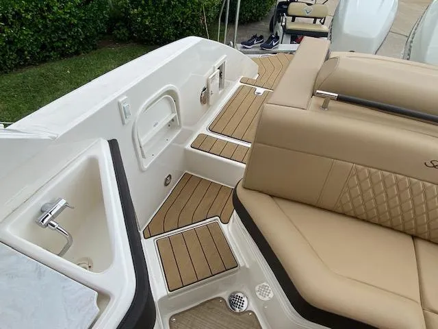 Slide: The Image of 2023 Sea Ray SLX 310 OB boat interior with tan seating and teak flooring. - 36