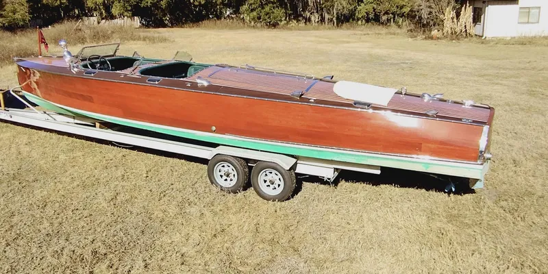 Slide: The Image of 1988 Hacker-Craft 30 Triple Cockpit boat on trailer in grassy field. - 2
