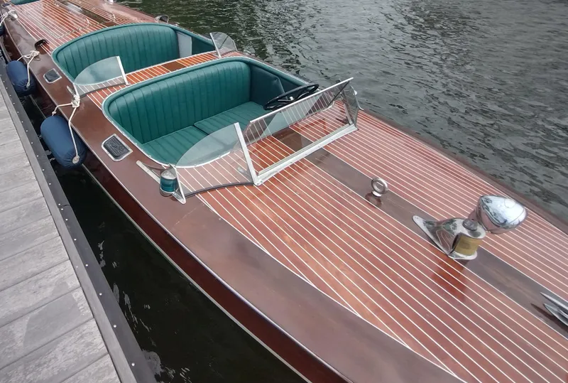 Slide: The Image of 1988 Hacker-Craft 30 Triple Cockpit boat with wooden deck and green seating, docked by the water. - 25