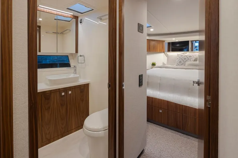 Slide: The Image of 2024 Riviera 46 Sports Motor Yacht interior, featuring a modern bathroom and cozy bedroom. - 11