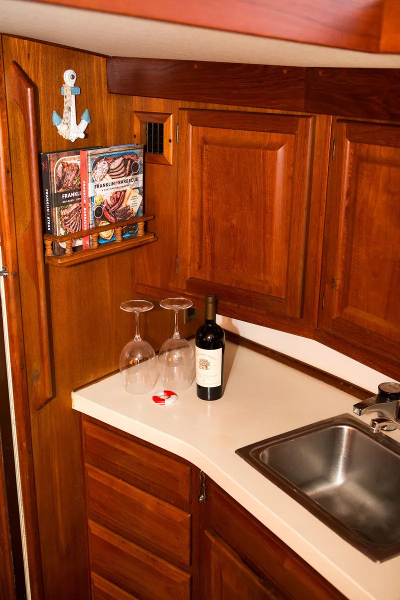 Slide: The Image of Wooden kitchen interior of 1986 Viking 41 boat with wine bottle, glasses, and cookbooks. - 13