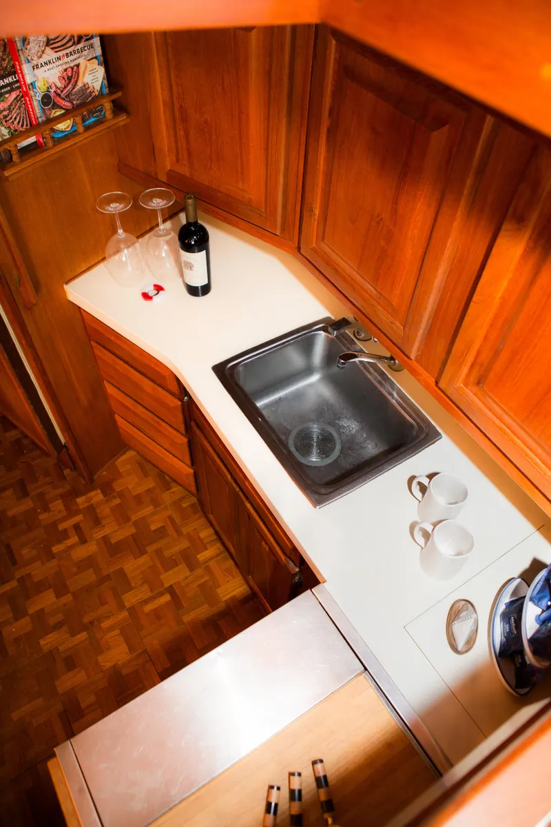 Slide: The Image of 1986 Viking 41 yacht kitchen with wooden cabinets, sink, wine bottle, and glasses. - 15