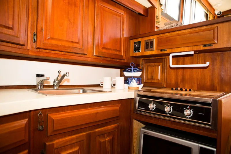 Slide: The Image of 1986 Viking 41 boat kitchen with wooden cabinets, sink, stove, and microwave. - 16
