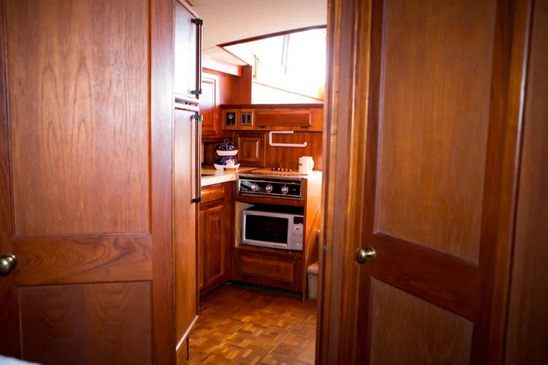 Slide: The Image of 1986 Viking 41 yacht kitchen with wooden cabinetry, stove, microwave, and refrigerator. - 19