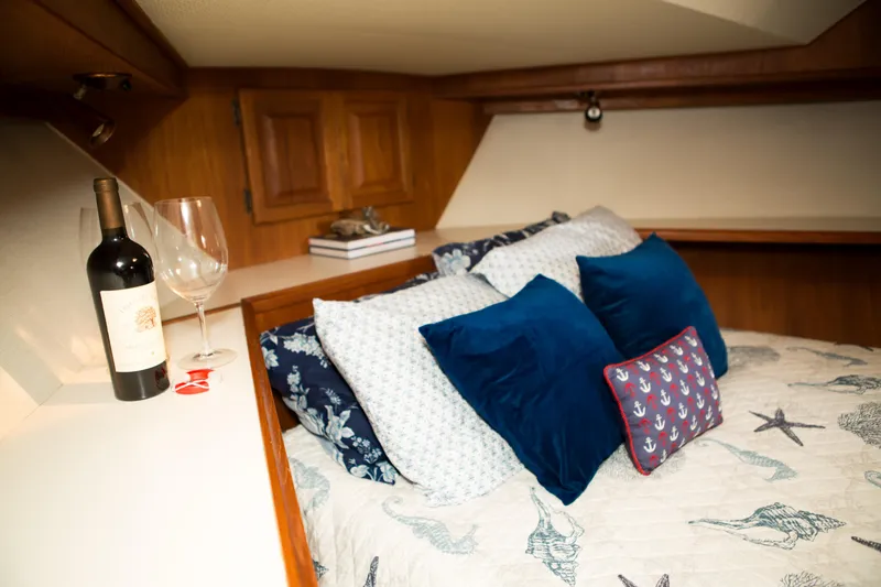 Slide: The Image of Cozy cabin interior of a 1986 Viking 41 boat with wine and nautical-themed bedding. - 23
