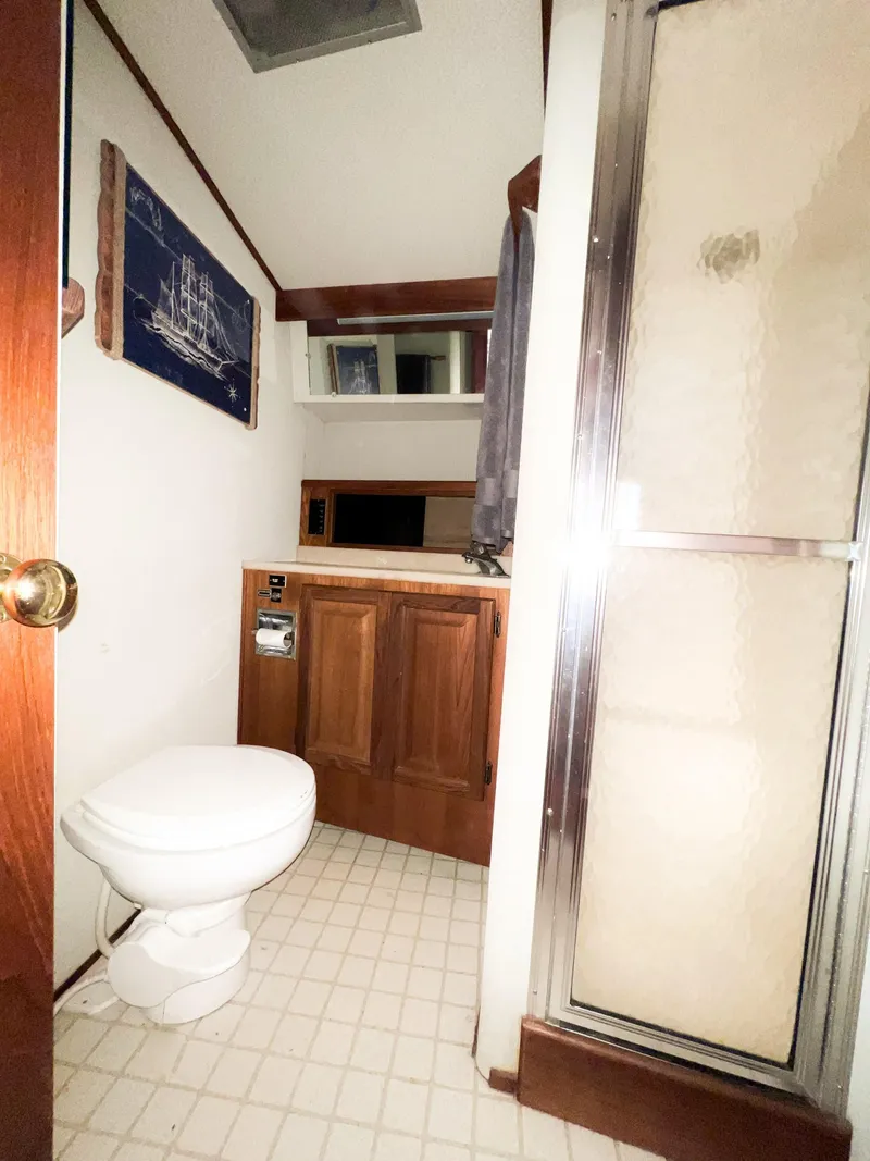 Slide: The Image of 1986 Viking 41 yacht bathroom with shower, toilet, wooden cabinets, and nautical decor. - 26