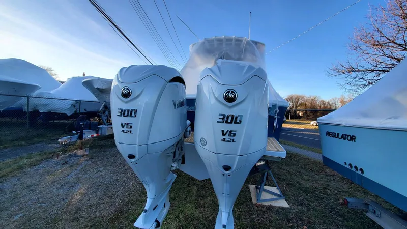 Slide: The Image of 2023 Regulator 28 boat with twin Yamaha 300 V6 engines, parked outdoors. - 12