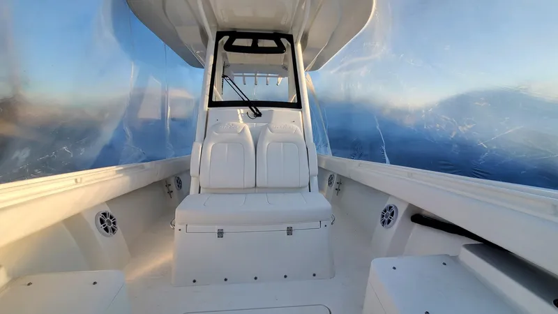 Slide: The Image of 2023 Regulator 28 boat interior with white seating and clear enclosure, ocean view. - 18