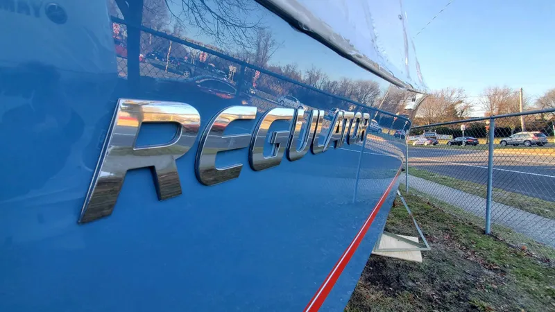 Slide: The Image of 2023 Regulator 28 boat with metallic logo on blue hull. - 21