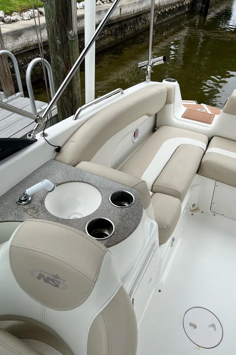 Slide: The Image of 2017 NauticStar 243DC Sport Deck boat interior with beige seating and cup holders. - 18