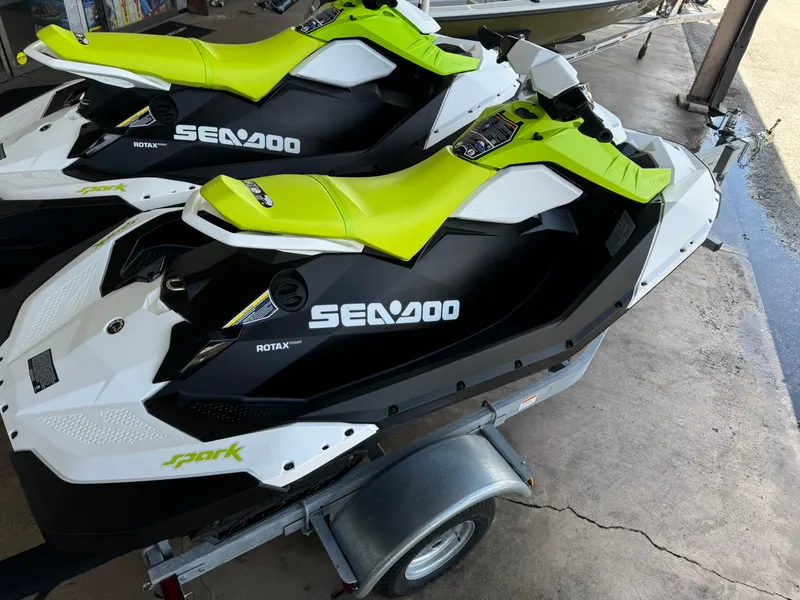 Slide: The Image of 2023 Sea-Doo Spark 2-up Rotax 900 ACE jet skis with vibrant green seats on a trailer. - 2