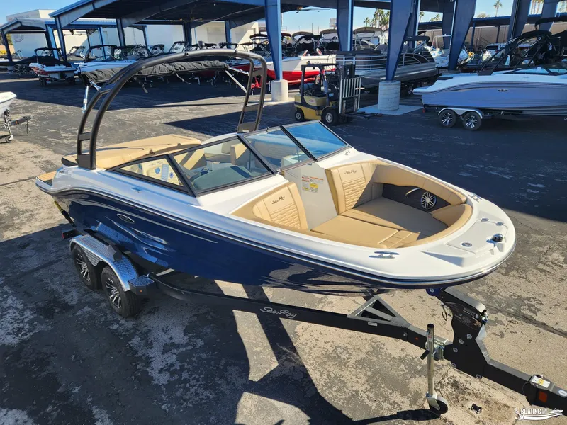 Slide: The Image of 2023 Sea Ray SPX 190 boat on trailer, blue and white exterior, parked in marina. - 2