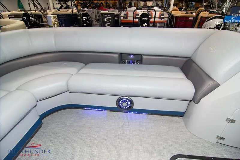Slide: The Image of 2022 Manitou 25 Oasis SR SHP boat interior with gray seating and blue LED lighting. - 11