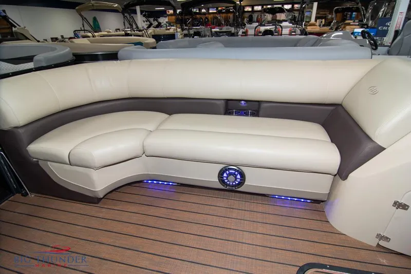 Slide: The Image of 2022 Manitou 25 Oasis SR SHP boat interior with beige seating and blue LED lights. - 12