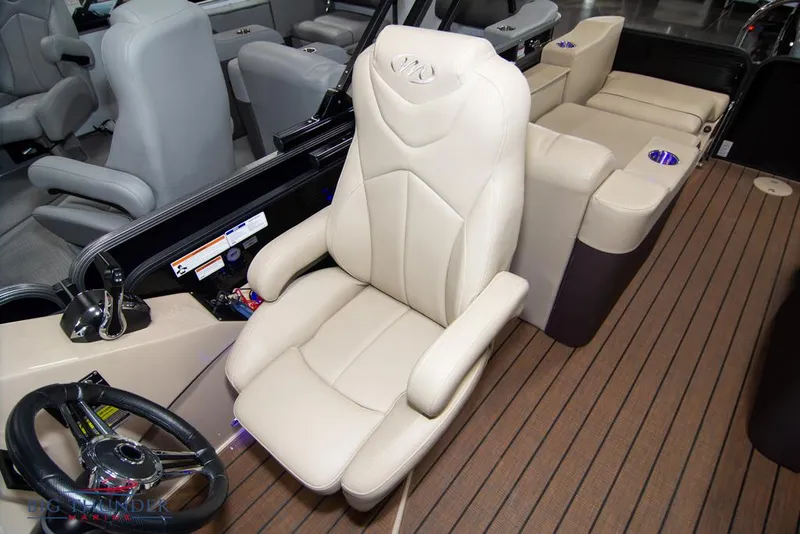 Slide: The Image of 2022 Manitou 25 Oasis SR SHP boat interior with luxurious captain's chair and steering wheel. - 28