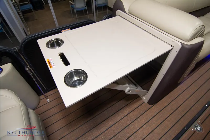 Slide: The Image of 2022 Manitou 25 Oasis SR SHP boat interior with foldable table and cup holders. - 33