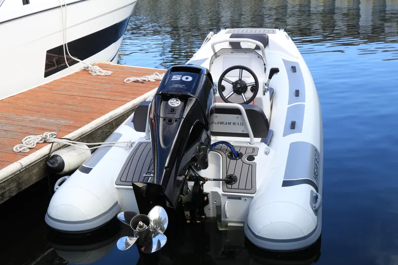 Slide: The Image of 2023 Highfield 390 Sport boat docked, featuring a powerful outboard motor. - 0