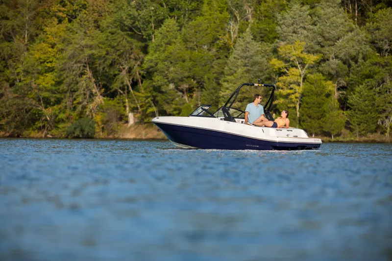 Slide: The Image of 2023 Bayliner VR4 OB boat cruising on a serene lake with lush green forest backdrop. - 28