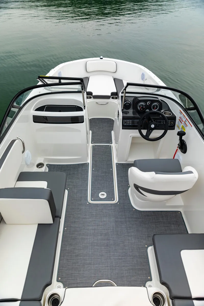 Slide: The Image of 2023 Bayliner VR4 OB boat interior with seating, steering wheel, and dashboard on calm water. - 9