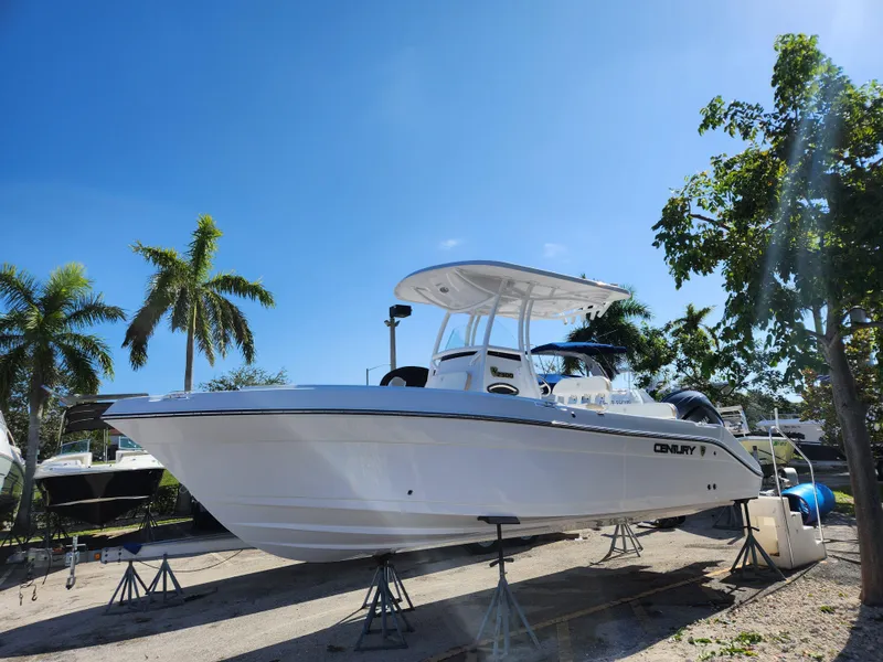 Slide: The Image of 2023 Century 2301 Center Console boat on stands, surrounded by palm trees under a clear blue sky. - 0