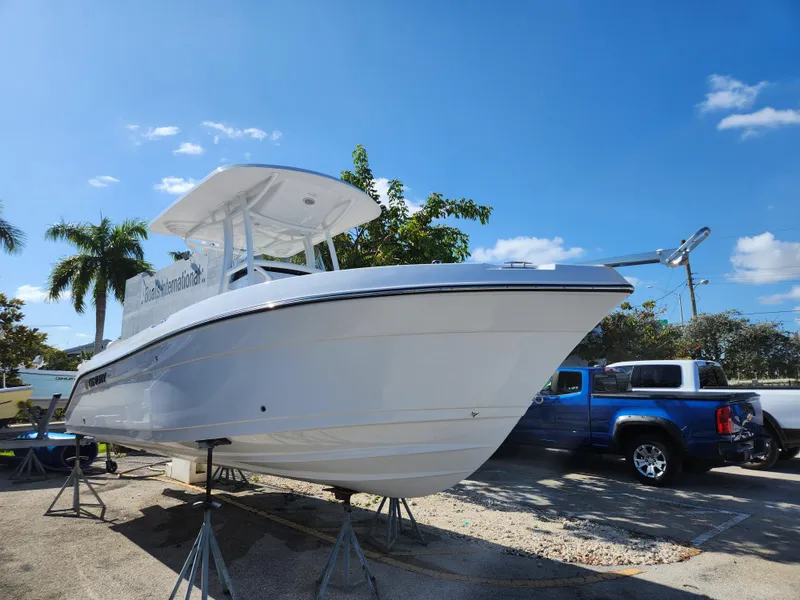 Slide: The Image of 2023 Century 2301 Center Console boat on stands, clear sky, palm trees in background. - 1