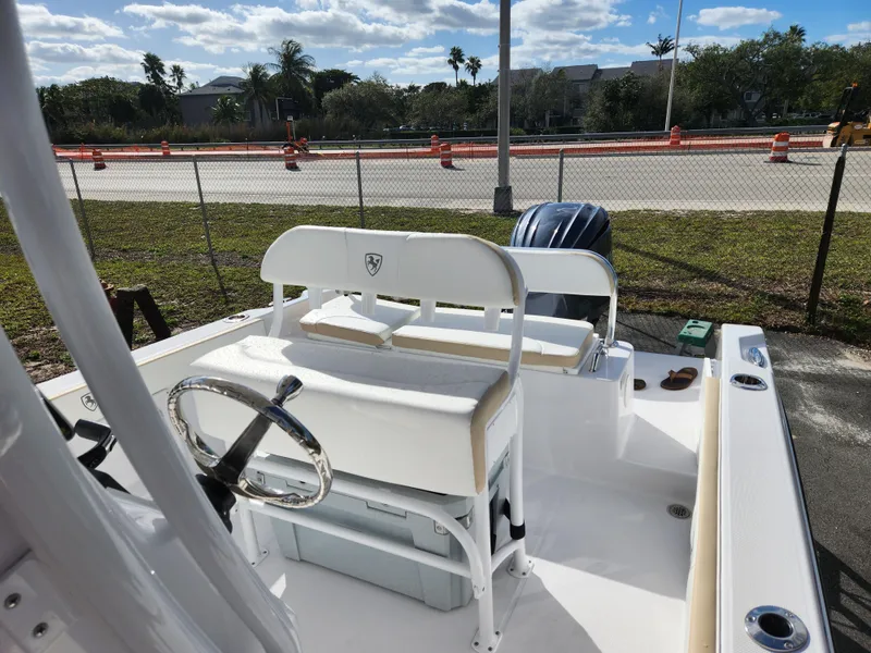 Slide: The Image of 2023 Century 2301 Center Console boat with seating and steering wheel, parked outdoors. - 39