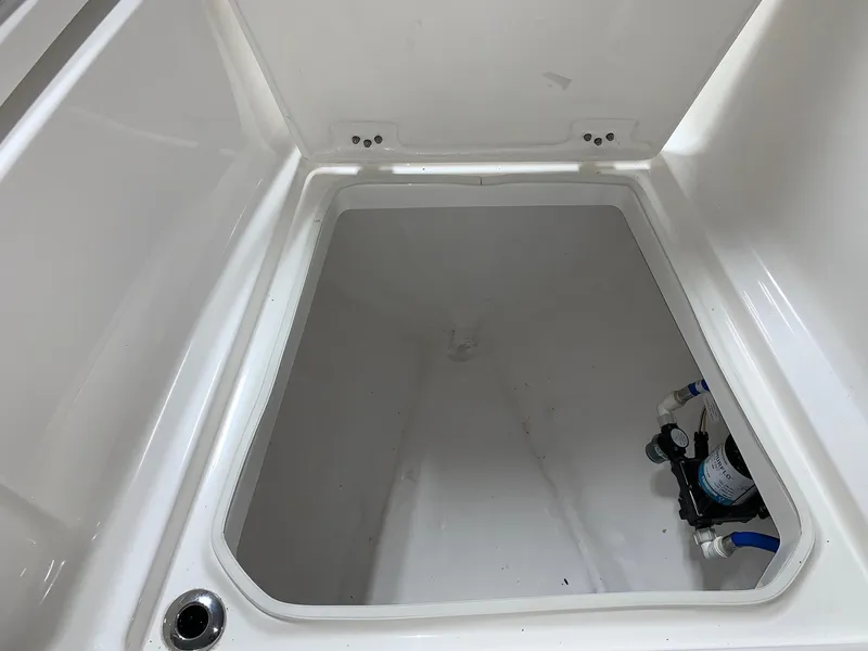 Slide: The Image of 2026 Robalo R270 storage compartment, white interior, with visible plumbing components. - 12