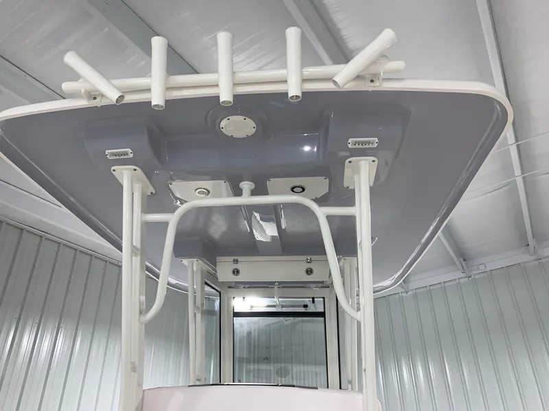 Slide: The Image of 2026 Robalo R270 boat T-top with rod holders in a storage facility. - 16
