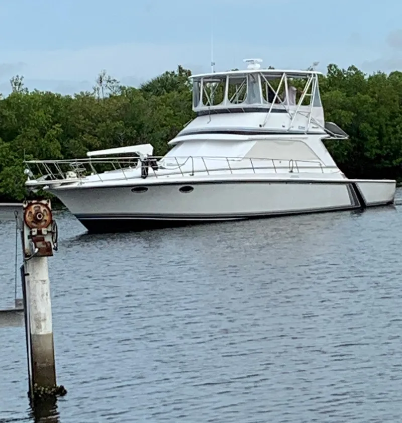 Slide: The Image of 1986 Trojan 14 Meter yacht anchored on a calm river with lush greenery. - 1