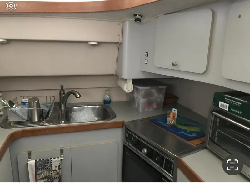 Slide: The Image of Compact kitchen in a 1986 Trojan 14 Meter boat with sink, stove, and storage cabinets. - 2