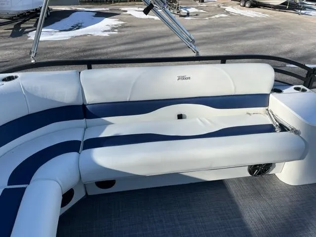 Slide: The Image of 2023 JC 25 Neptoon boat with white and blue seating, outdoor setting. - 7