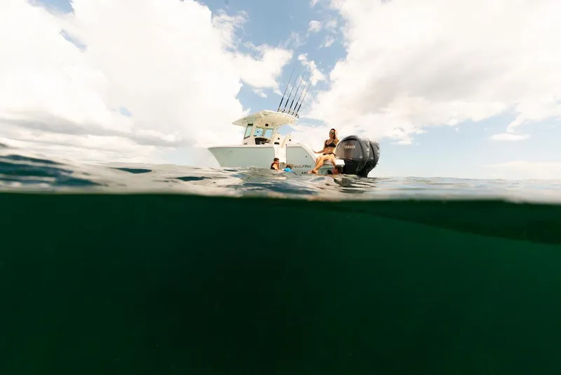 Slide: The Image of 2024 Sailfish 312 CC boat on open water, people swimming nearby. - 22