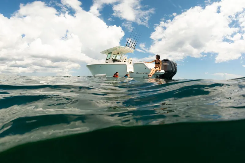 Slide: The Image of 2024 Sailfish 312 CC boat on open water, people swimming nearby under cloudy sky. - 25