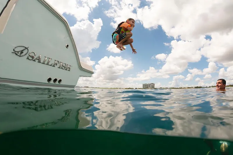 Slide: The Image of Child jumping off 2024 Sailfish 312 CC boat into water, under a sunny sky. - 29