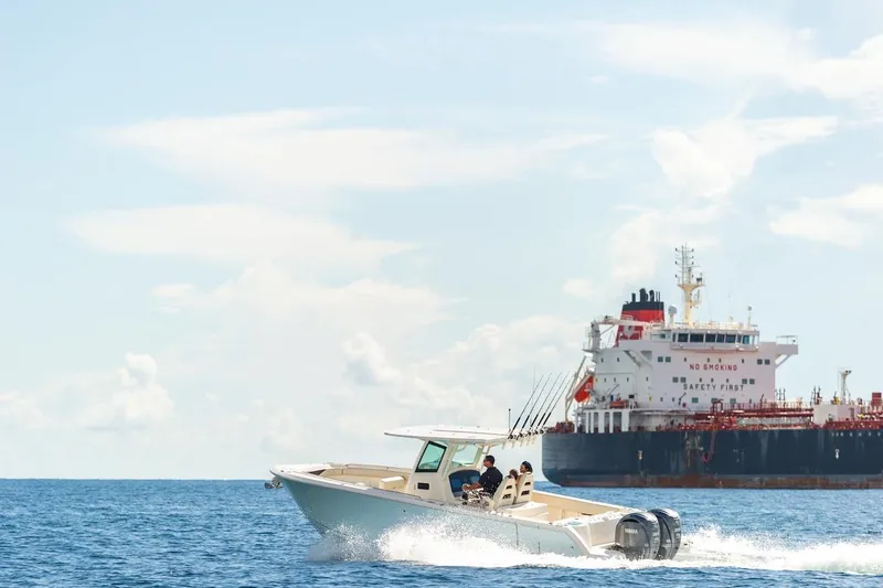 Slide: The Image of 2024 Sailfish 312 CC boat cruising near a large cargo ship. - 3