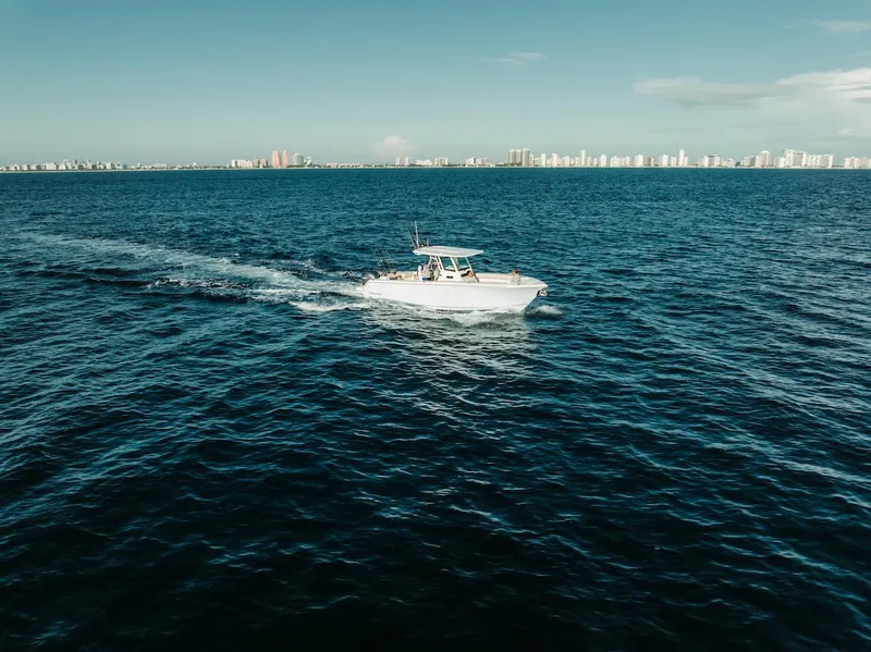 Slide: The Image of 2024 Sailfish 312 CC boat cruising on open ocean with city skyline in background. - 36