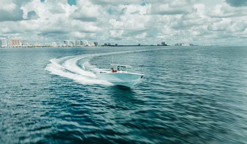 Slide: The Image of 2024 Sailfish 312 CC boat cruising on open water under cloudy sky. - 44