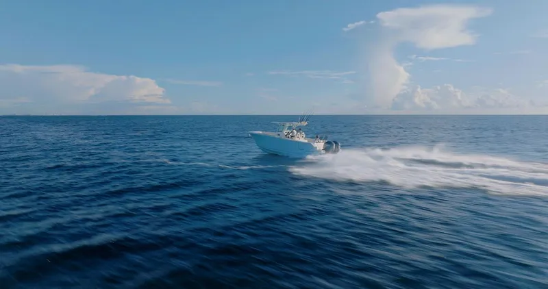 Slide: The Image of 2024 Sailfish 312 CC boat speeding across open ocean under clear blue sky. - 45