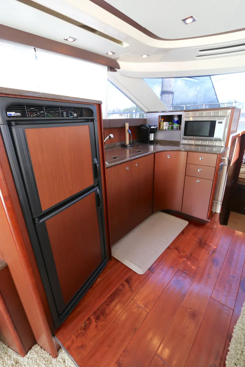 Slide: The Image of 2013 Meridian 441 Sedan yacht kitchen with wood flooring, fridge, microwave, and modern cabinetry. - 3