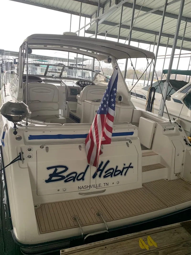 Slide: The Image of Regal 402 boat from 1999 named "Bad Habit" docked with American flag. - 12