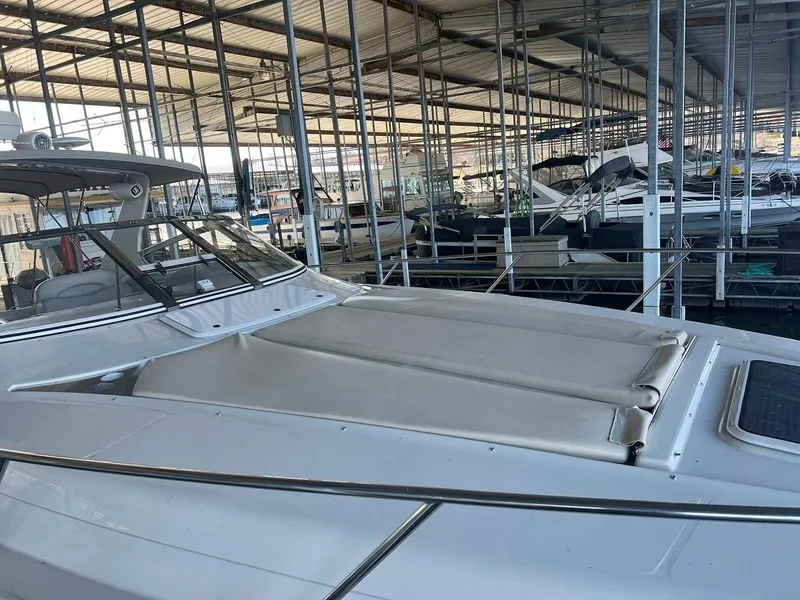 Slide: The Image of 1999 Regal 402 boat docked in a covered marina, showcasing sleek design and spacious deck. - 16