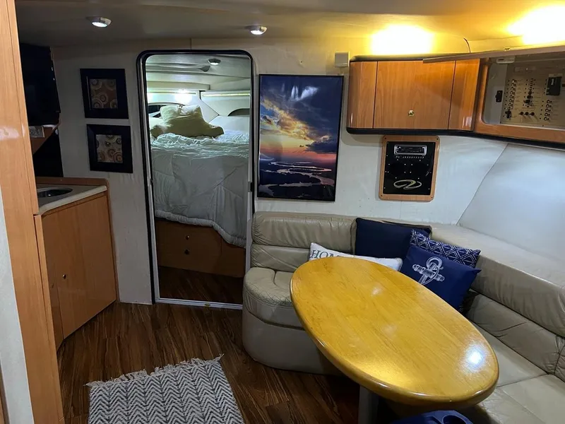 Slide: The Image of 1999 Regal 402 yacht interior with cozy seating, wooden table, and nautical decor. - 31